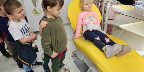 Dziewczynka na fotelu stomatologicznym i towarzyszące dzieci