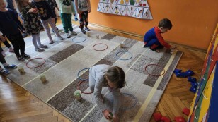 Dzieci w konkurencji sportowej, układają piłeczki na kubkach